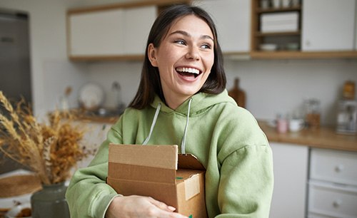 Woman in green hoody hugging box smiling