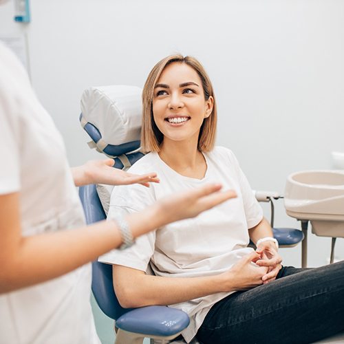 Patient in treatment chair smiling at dentist assistant