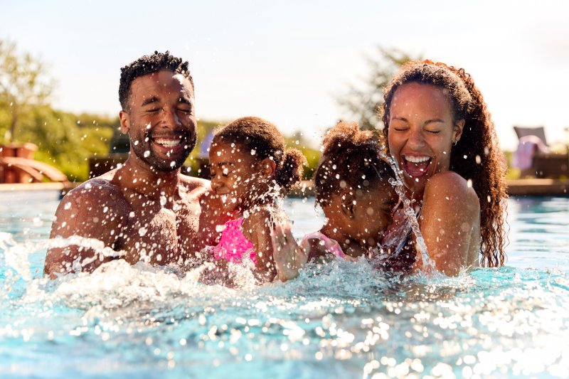 Family enjoying summer in the pool with dental implants